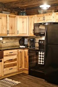 a kitchen with wooden cabinets and a black refrigerator at Renovated Cottage with Spa Surrounded by Beautiful Hiking Trails in Ohio in Deersville +15 photos
