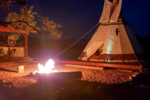 a tent with a fire in front of it at night at Unique Tipi Accommodation for a Glamping Experience near Las Vegas, Nevada in Sandy Valley +12 photos