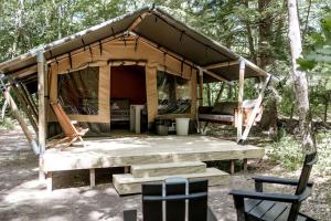 een tent in het bos met een tafel en stoelen bij Magnificent Safari Tent with Sauna and Fire Pit in North Woodstock, New Hampshire in Woodstock