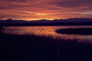 a sunset over a body of water with mountains in the background at Romantic Getaway for Two in a Peaceful Suite near Coeur d'Alene, Idaho in Careywood