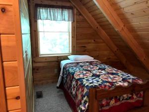 une chambre avec un lit dans une cabane en rondins dans l'établissement Secluded Cabin Rental in the Forest near Beckley, West Virginia, à Hico