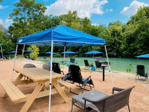 a picnic table with a blue tent on a beach at Stunning Glamping Destination Ideal for a Relaxing Vacation: Luxury Safari Tent on the San Marcos River near Kingsbury, Texas in Staples