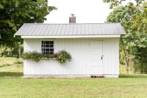 ein weißer Schuppen mit einem Fenster und Blumen darauf in der Unterkunft Elegant Cottage Rental for Groups near Greensburg, Kentucky in Columbia