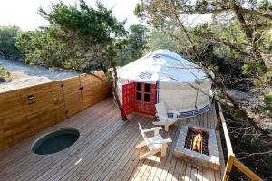 Hammetts CrossingにあるChrissie Ger in Dripping Springs, TXのデッキに椅子と暖炉があるパオ