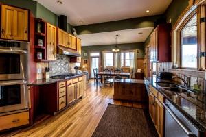Il comprend une grande cuisine dotée de parquet et d'armoires en bois. dans l'établissement Modern and Cozy Cabin Rental Between Mountains and River in Northern Georgia, à Mineral Bluff