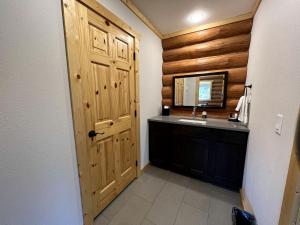 a bathroom with a sink and a wooden door at Cozy 1-Bedroom Log Cabin with Full Kitchen & Wi-Fi | Bonners Ferry, Idaho Retreat in Bonners Ferry +4 photos