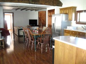 a kitchen with a table and chairs and a refrigerator at Unique Renovated Barn Rental with Pond near Cooperstown, New York in Fly Creek