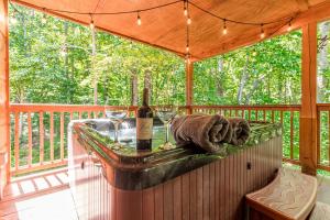 a wooden deck with a table with wine bottles and glasses at Relaxing Cabin with Screened Porch in Sautee Nacoochee, Georgia in Sautee Nacoochee