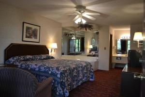 Habitación de hotel con cama y ventilador de techo. en Apple Blossom Inn, en Eureka Springs