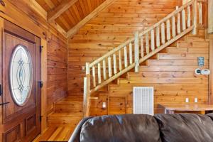 a living room with a couch and stairs in a cabin at Stunning Cabin with Hot-tub, Fire Pit and Games in Stanton, Kentucky in Stanton