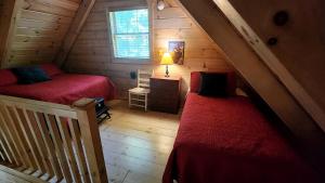 una habitación con dos camas en una cabaña de madera en Nostalgic Riverside Cabin Haven Near New River, Virginia, en Galax