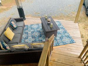 eine Couch auf einer Holzterrasse mit einem Tisch in der Unterkunft Beautiful Cottage with Fire Pit and Barbecue in Dunnellon, Florida in Dunnellon + 26 Fotos