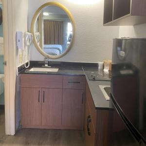 a kitchen with a sink and a mirror at HomeTowne Studios by Red Roof Buffalo - Niagara Airport in Williamsville