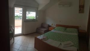 a bedroom with a bed and a chair and a window at Apartments Juric in Baška Voda
