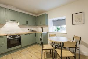 eine Küche mit grünen Schränken sowie einem Tisch und Stühlen in der Unterkunft Contractor's Cottage Kildare 5 Double Beds in Bodenstown + 7 Fotos