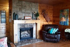 - un salon avec une cheminée et un fauteuil en cuir dans l'établissement Wonderful Mountain Cabin Rental with a Fire Pit in Smithville, Oklahoma, à Big Cedar
