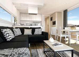 a living room with a black couch and a kitchen at Magical Retreat with a Pool Ideal for Luxury Camping, Austria in Unterlibitsch