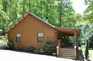 eine kleine Blockhütte mit einer Treppe, die dorthin führt in der Unterkunft Lovely Rustic Cabin Secluded in the Woods near Maggie Valley, North Carolina in Cherokee