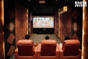 two people sitting in chairs watching a movie on a screen at StayVista at Vacanza Villa - Pool, Lawn & Theatre in Jaipur