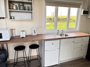 a kitchen with a counter with stools and a sink at Fantastic Off-Grid Tiny House Fully Equipped with Beautiful Countryside Views in Ireland in Eighter