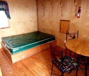 a room with a bed and a table and chair at Charming Wooden Cabin with Fire Pit near West Yellowstone, Montana in Lakeview