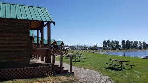 a group of picnic tables in a field next to a lake at Charming Wooden Cabin with Fire Pit near West Yellowstone, Montana in Lakeview