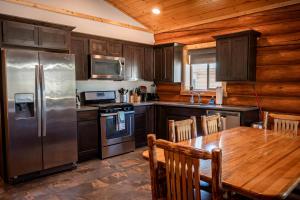eine Küche mit Tisch und Edelstahlkühlschrank in der Unterkunft Spacious Pet-Friendly Log Cabin with King Bed & Full Kitchen | Bonners Ferry, Idaho Retreat in Bonners Ferry