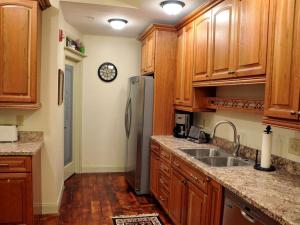 une cuisine avec des armoires en bois et un réfrigérateur en acier inoxydable dans l'établissement Spacious Cottage Rental with Creek Views near Harrisburg and Hershey, Pennsylvania, à Highspire