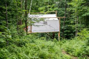 a sign in the middle of a forest at Treehouse-Style Tent Rental in the White Mountain National Forest of New Hampshire in Chatham