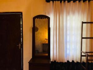 a mirror next to a window with a curtain at Nethu Freedom Cottage in Weligama