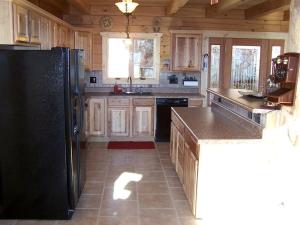 une cuisine avec des armoires en bois et un réfrigérateur noir dans l'établissement Luxury Vacation Rental with a Hot Tub for Rent in Clyde, North Carolina, à Crabtree