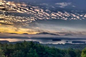 vista su un lago nebbioso con alberi e montagne di Regal Castle Suite for a Luxury Getaway to Lake George in Upstate New York a Bolton Landing