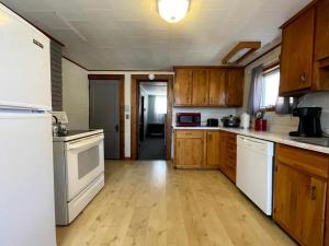 a kitchen with white appliances and wooden cabinets at Embrace Nature in this Breathtaking Cottage in Portage Lake, Maine in Portage Lake Municipal Seaplane Base +19 photos