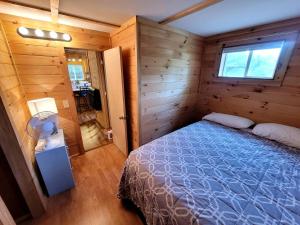 a bedroom with a bed in a wooden cabin at Cozy Lakeside Log Cabin with Kayaks & Arcade Access near Trails in Bitely, Michigan in Bitely