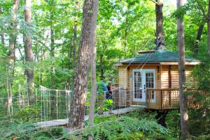 a tree house in the woods with people in it at Stunning Tree House Rental in the Forest near Beckley, West Virginia in Hico