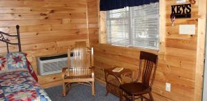 a bedroom with wooden walls and two chairs and a bed at Flintstone Cozy Cabin for Places to Visit in Maryland in Flintstone