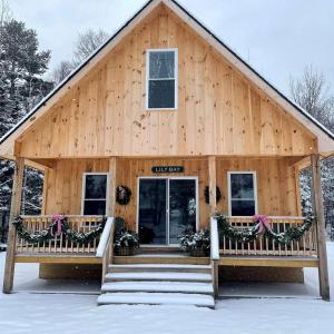 une cabane en rondins avec un porche dans la neige dans l'établissement Incredible Wooden Cabin with Fire Pit and Barbecue in Greenville, Maine, à Greenville