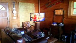Una sala de estar con un sofá y un televisor de pantalla plana. en Log Cabin in the Clouds with Spectacular Views in Northern Chattanooga, Tennessee, en Whitwell