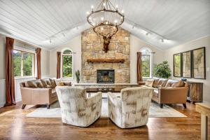 a living room with a stone fireplace and a chandelier at Exquisite Cabin with Amazing Interior and Exterior in Sarahsville, Ohio in Senecaville