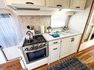 a kitchen with a stove and a sink at Riverside Airsteram Adventure in Colorado - Relaxation by the Water in Grand Junction in Grand Junction +2 photos