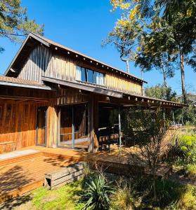ein großes Holzhaus mit Terrasse und Bäumen in der Unterkunft Charmant Chalet au bord du lac in Lacanau