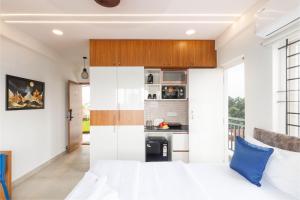 a bedroom with a white bed and a kitchen at OBS Luxury Suites - JP Nagar in Bangalore