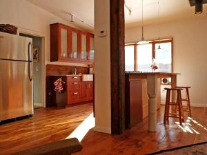 a kitchen with a stainless steel refrigerator and wooden floors at Luxury Open Floor Plan Studio Rental in Nine-Acre Sculpture Garden in the Adirondacks in Wells