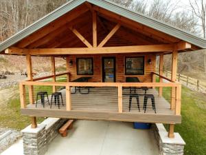 una baita di tronchi con terrazza arredata con sedie e tavoli. di Rustic Tree A-Frame with Original Design by Tappan Lake in Ohio  Altre 20 foto