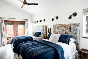 zwei Betten in einem Schlafzimmer mit weißen Wänden in der Unterkunft Modern Luxury Rental with Bohemian Decor near Antique Show in Round Top, Texas in Round Top
