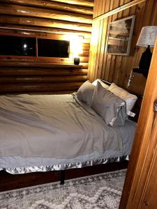 un lit dans une chambre avec un mur en bois dans l'établissement Charming Lakeside Cabin Bungalow with Timeless Rustic Beauty near Portage Lake in Maine, à Portage Lake Municipal Seaplane Base