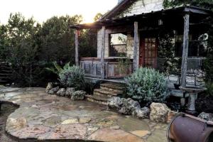 a small house with a stone patio and a porch at Blue Bird Cabin with Hot Tub in Texas Hill Country in Woodcreek