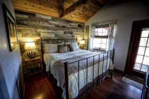 a bedroom with a bed and a wooden wall at Blue Bird Cabin with Hot Tub in Texas Hill Country in Woodcreek