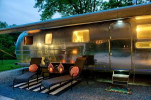 a silver train car with chairs sitting in front of it at Unique Accommodation for a Glamping Getaway in Columbia, Pennsylvania in Columbia