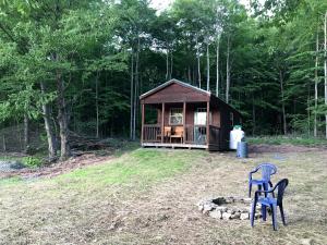 a cabin in the woods with two chairs in front of it at Log Cabin for Family Glamping Vacation near Cherry Springs State Park, Pennsylvania in Short Run